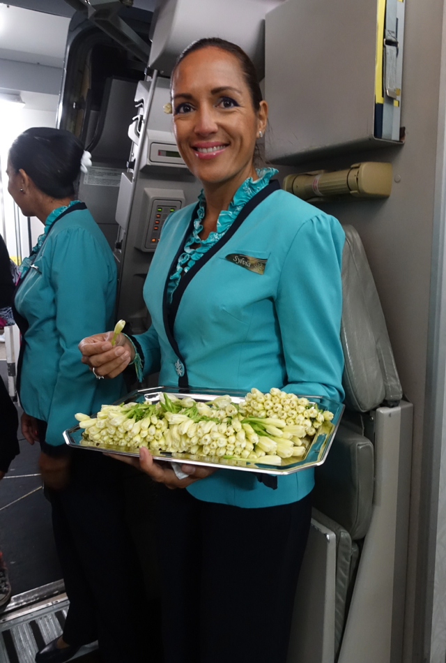 Air Tahiti Nui Flight Attendant Welcoming Passengers with Tiare Flowers